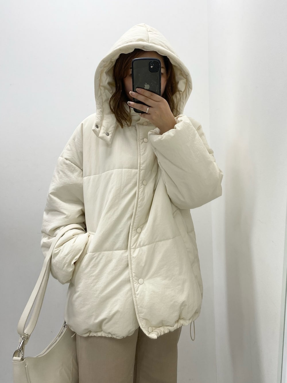 ホワイト系のダウンジャケット/コート、ホワイト系のショルダーバッグ、ベージュ系のデニムパンツを着用したレディースの秋コーディネートの2枚目の写真