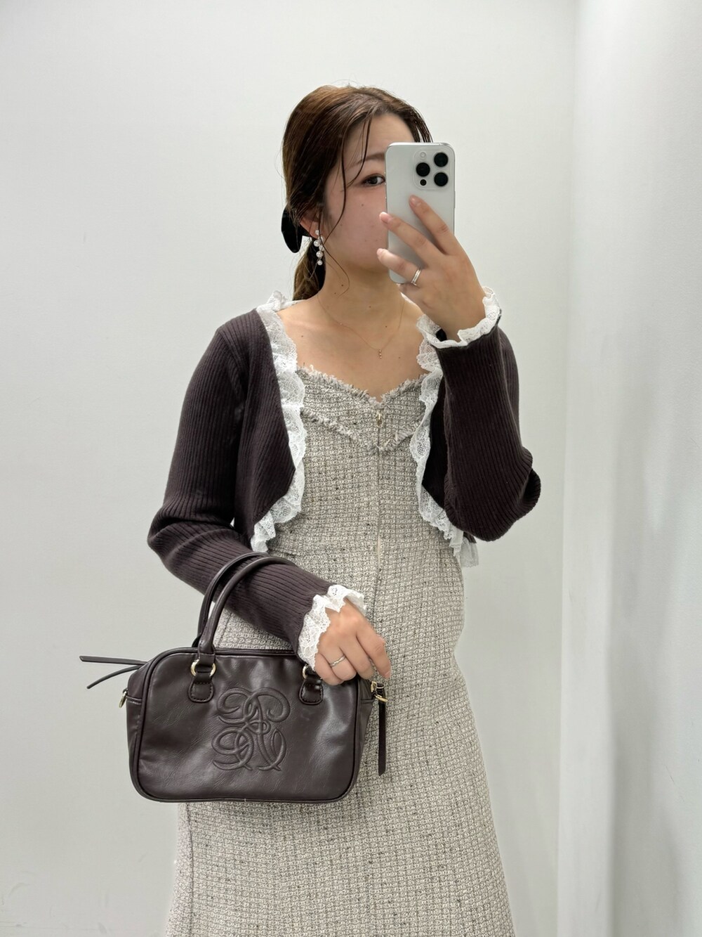 ブラウン系のカーディガン/ボレロ、ブラウン系のボストンバッグ、ホワイト系のブーツを着用したレディースの秋コーディネートの2枚目の写真