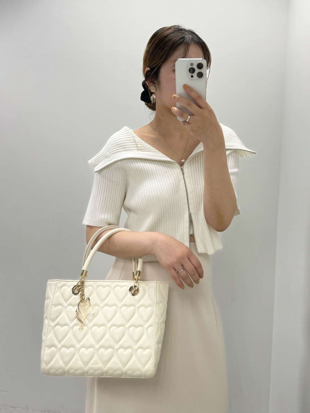 ホワイト系のニット/セーター、ベージュ系のスカート、ホワイト系のサンダルを着用したレディースの夏コーディネートの2枚目の写真