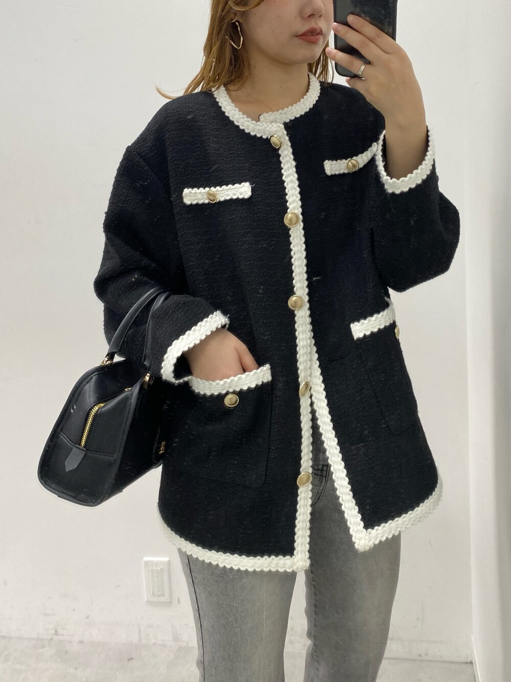 ブラック系のノーカラージャケット、ブラック系のハンドバッグ、ブラック系のデニムパンツを着用したレディースの冬コーディネートの2枚目の写真