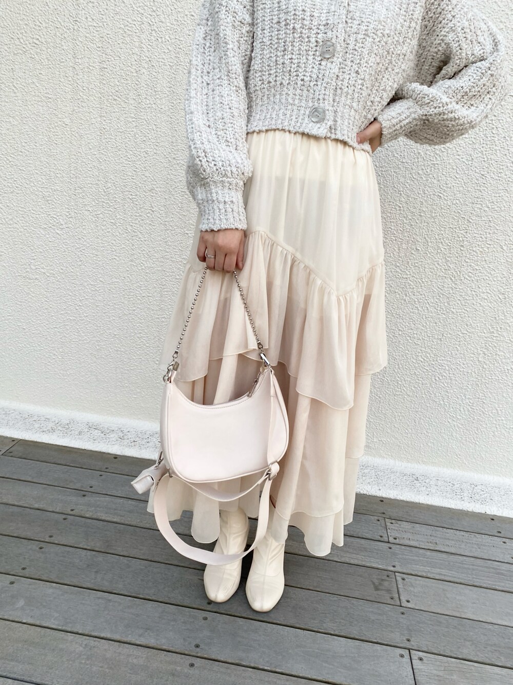 ホワイト系のショルダーバッグ、ホワイト系のスカート、ホワイト系のブーツを着用したレディースの冬コーディネートの3枚目の写真
