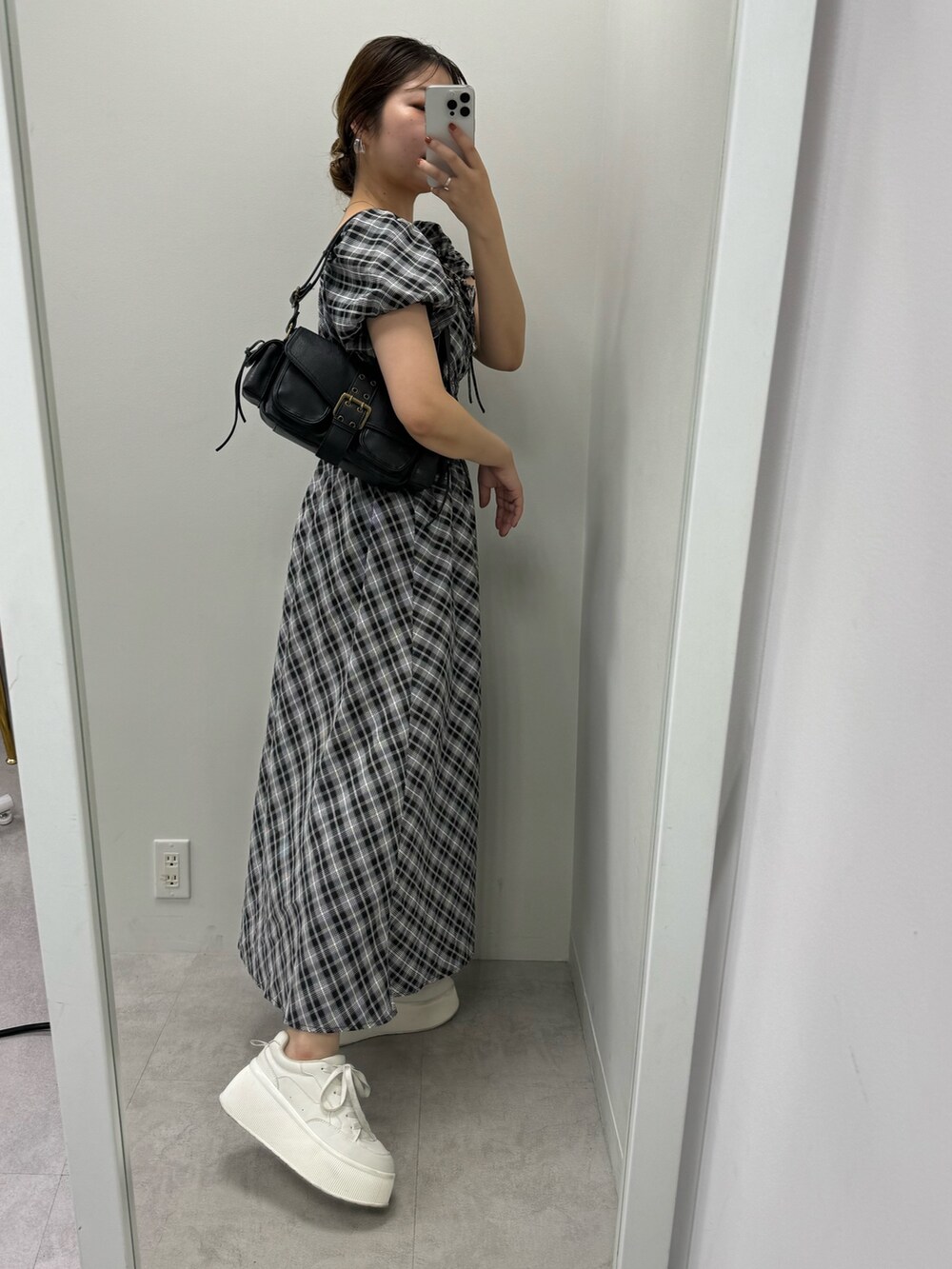 ブラック系のワンピース、ホワイト系のスニーカー、ブラック系のショルダーバッグを着用したレディースの夏コーディネートの2枚目の写真