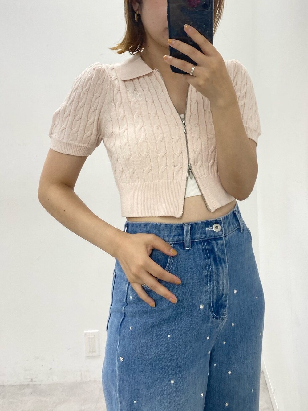 ピンク系のニット/セーター、ホワイト系のスニーカー、ブルー系のデニムパンツを着用したレディースの夏コーディネートの2枚目の写真