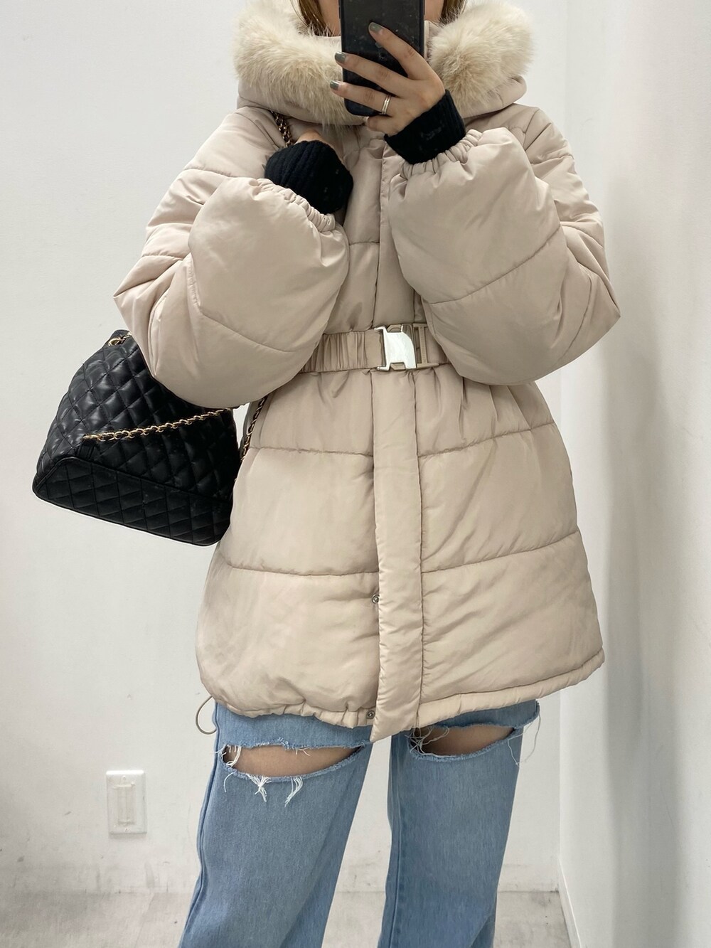 ベージュ系のダウンジャケット/コート、ブルー系のデニムパンツ、ブラック系のバックパック/リュックを着用したレディースの秋コーディネートの2枚目の写真