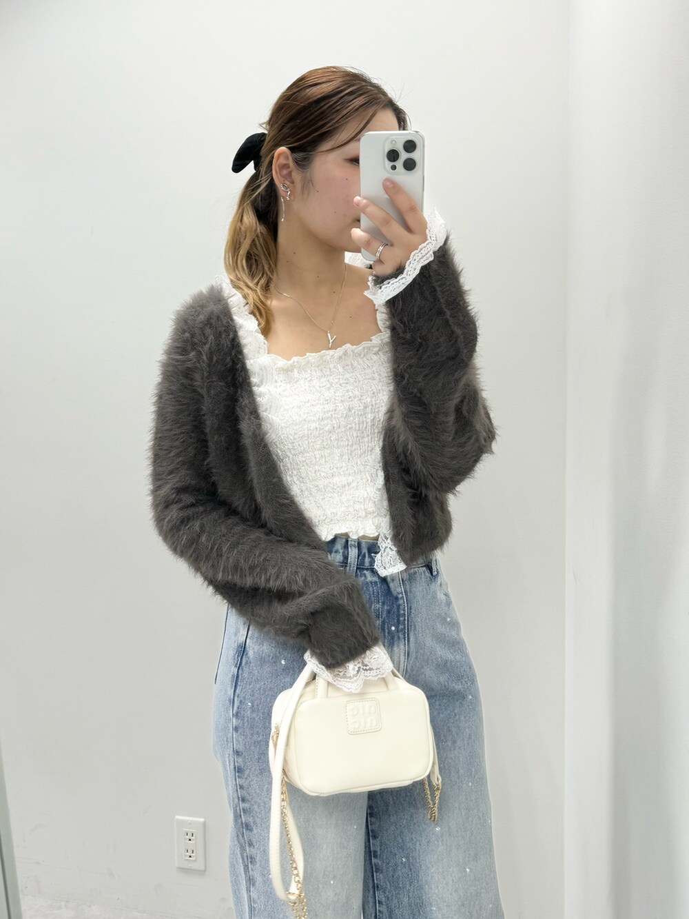 ブラウン系のカーディガン/ボレロ、ブルー系のデニムパンツ、ホワイト系のボストンバッグを着用したレディースの冬コーディネートの3枚目の写真