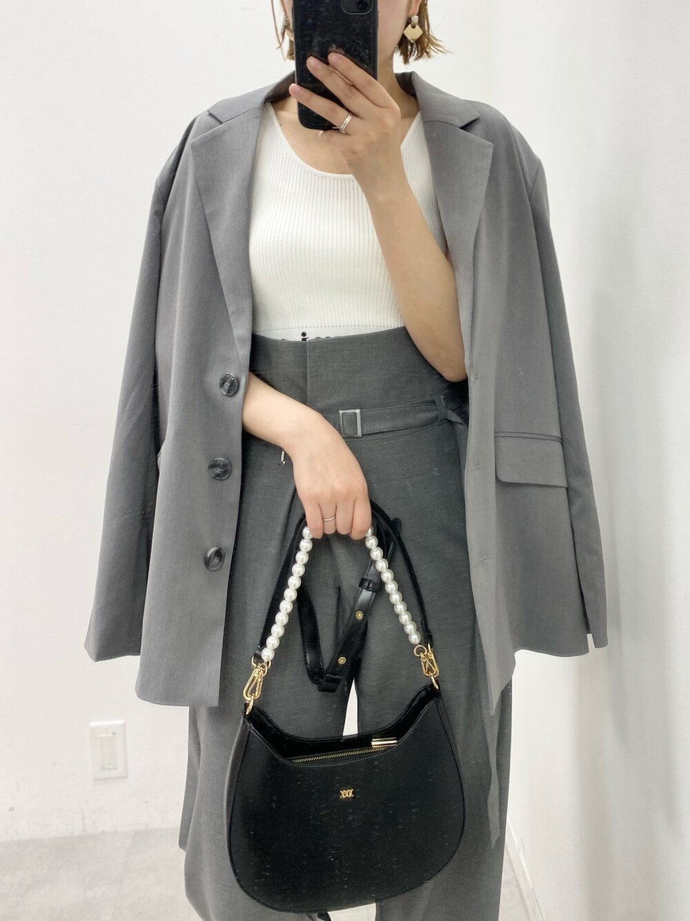 グレー系のテーラードジャケット、グレー系のスラックス、ホワイト系のタンクトップを着用したレディースの春コーディネートの2枚目の写真