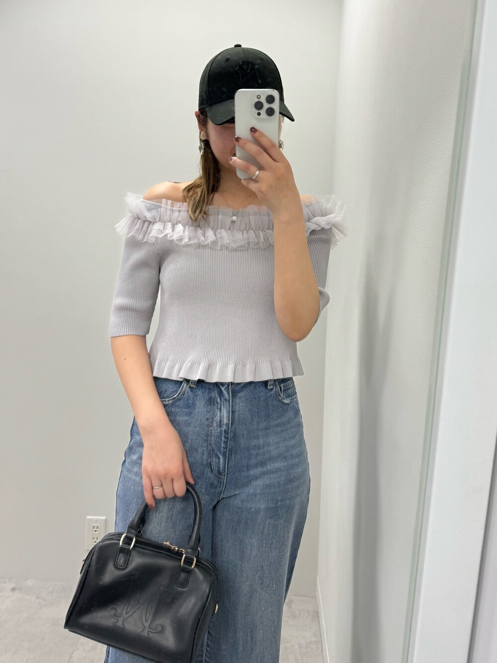 グレー系のニット/セーター、ブルー系のデニムパンツ、ブラック系のボストンバッグを着用したレディースの春コーディネートの2枚目の写真