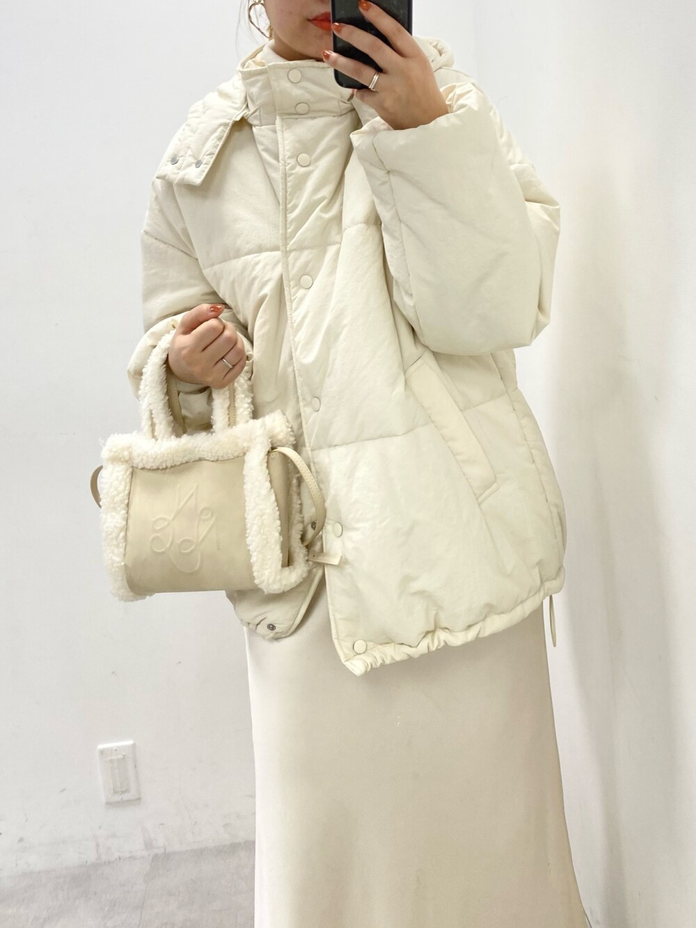 ホワイト系のダウンジャケット/コート、ホワイト系のニット/セーター、ホワイト系のスカートを着用したレディースの秋コーディネートの2枚目の写真
