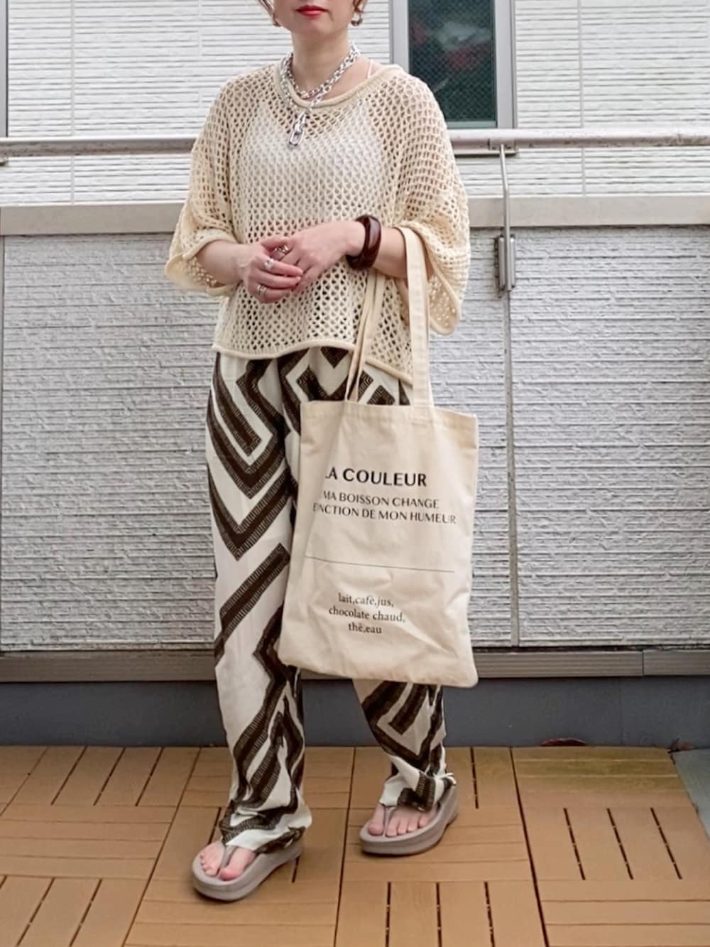 ホワイト系のニット/セーター、ホワイト系のその他パンツ、ホワイト系のトートバッグを着用したレディースの夏コーディネートの2枚目の写真