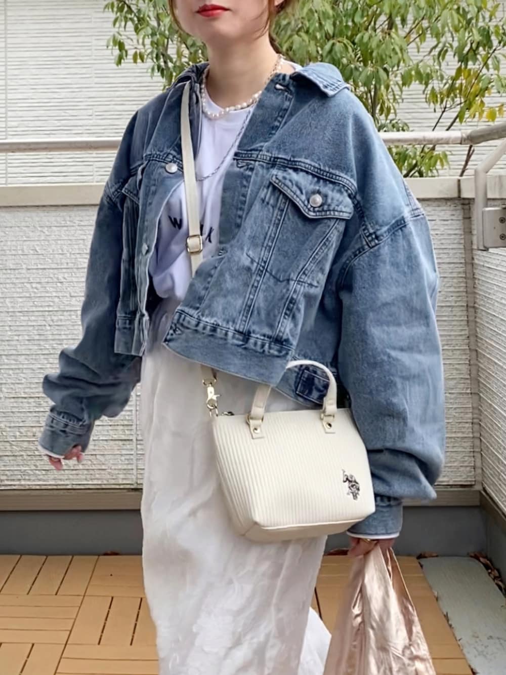 ブルー系のデニムジャケット、ホワイト系のスカート、ホワイト系のショルダーバッグを着用したレディースの春コーディネートの4枚目の写真