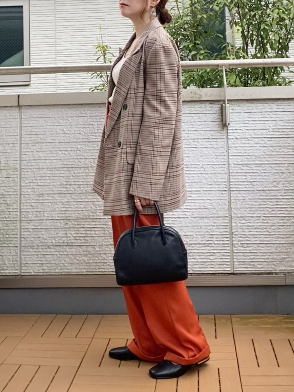 ブラウン系のテーラードジャケット、オレンジ系のスラックス、ブラック系のショルダーバッグを着用したレディースの秋コーディネートの2枚目の写真
