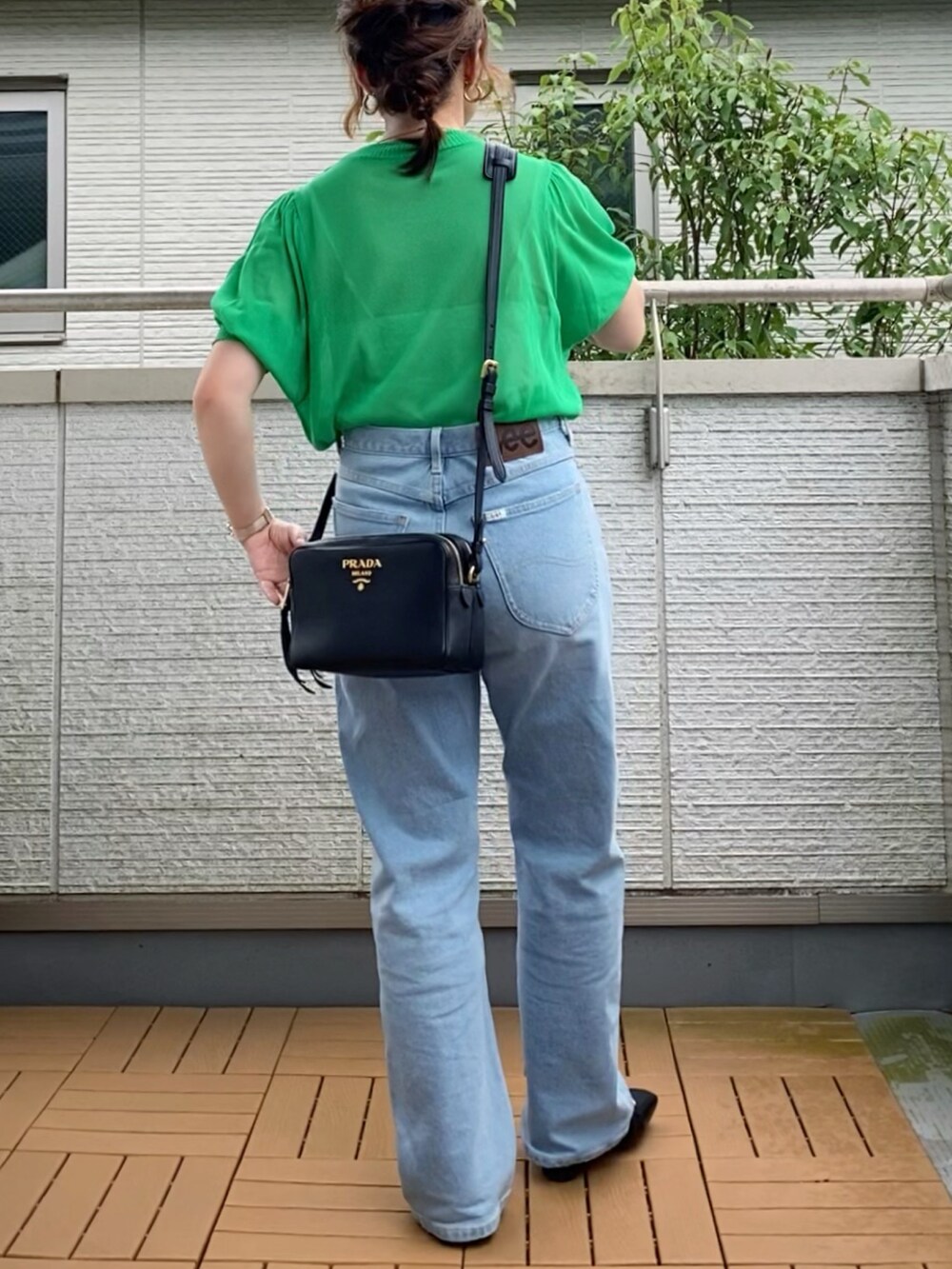 グリーン系のニット/セーター、ブルー系のデニムパンツ、ブラック系のパンプスを着用したレディースの夏コーディネートの3枚目の写真