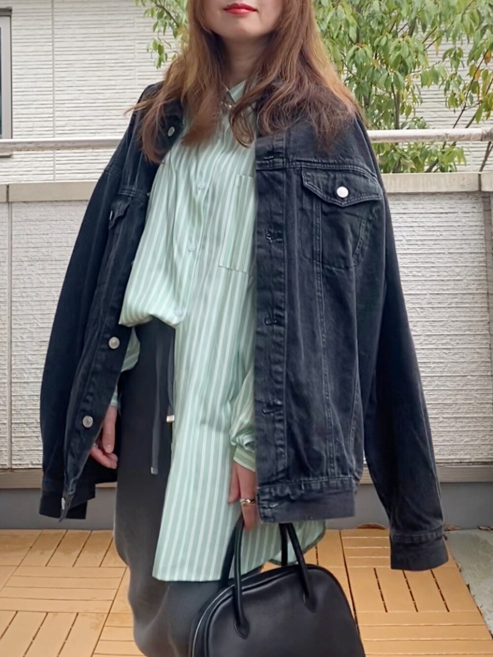 ブラック系のデニムジャケット、グリーン系のシャツ/ブラウス、グレー系のスカートを着用したレディースの春コーディネートの2枚目の写真