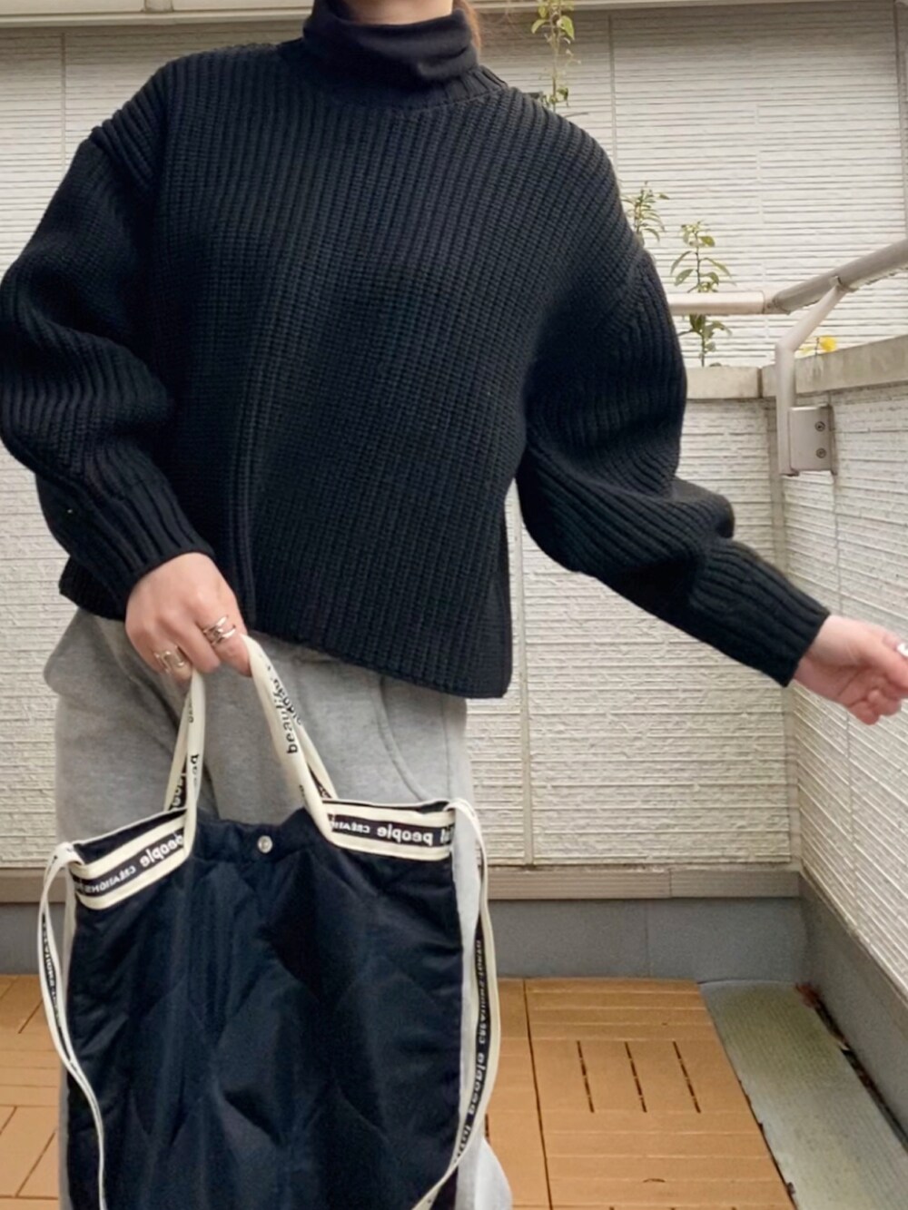 ブラック系のニット/セーター、ブラック系のTシャツ/カットソー、グレー系のスウェットパンツを着用したレディースの冬コーディネートの2枚目の写真
