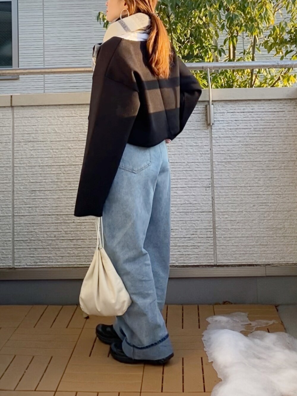 ブラック系のワンピース、ブルー系のデニムパンツ、ブラック系のスニーカーを着用したレディースの冬コーディネートの2枚目の写真