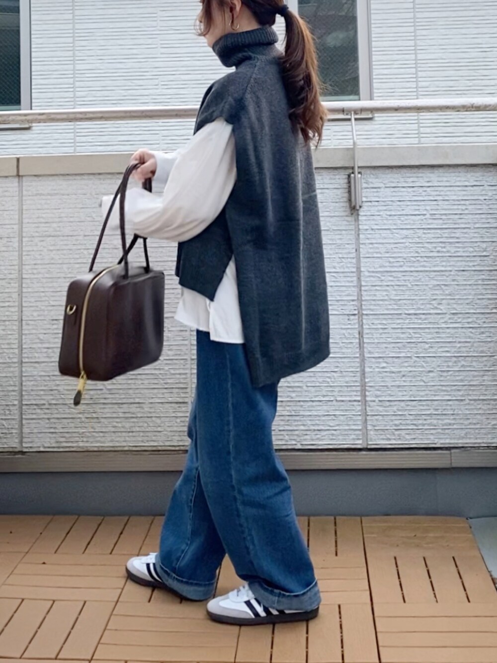 グレー系のベスト、ホワイト系のシャツ/ブラウス、ブルー系のデニムパンツを着用したレディースの冬コーディネートの3枚目の写真