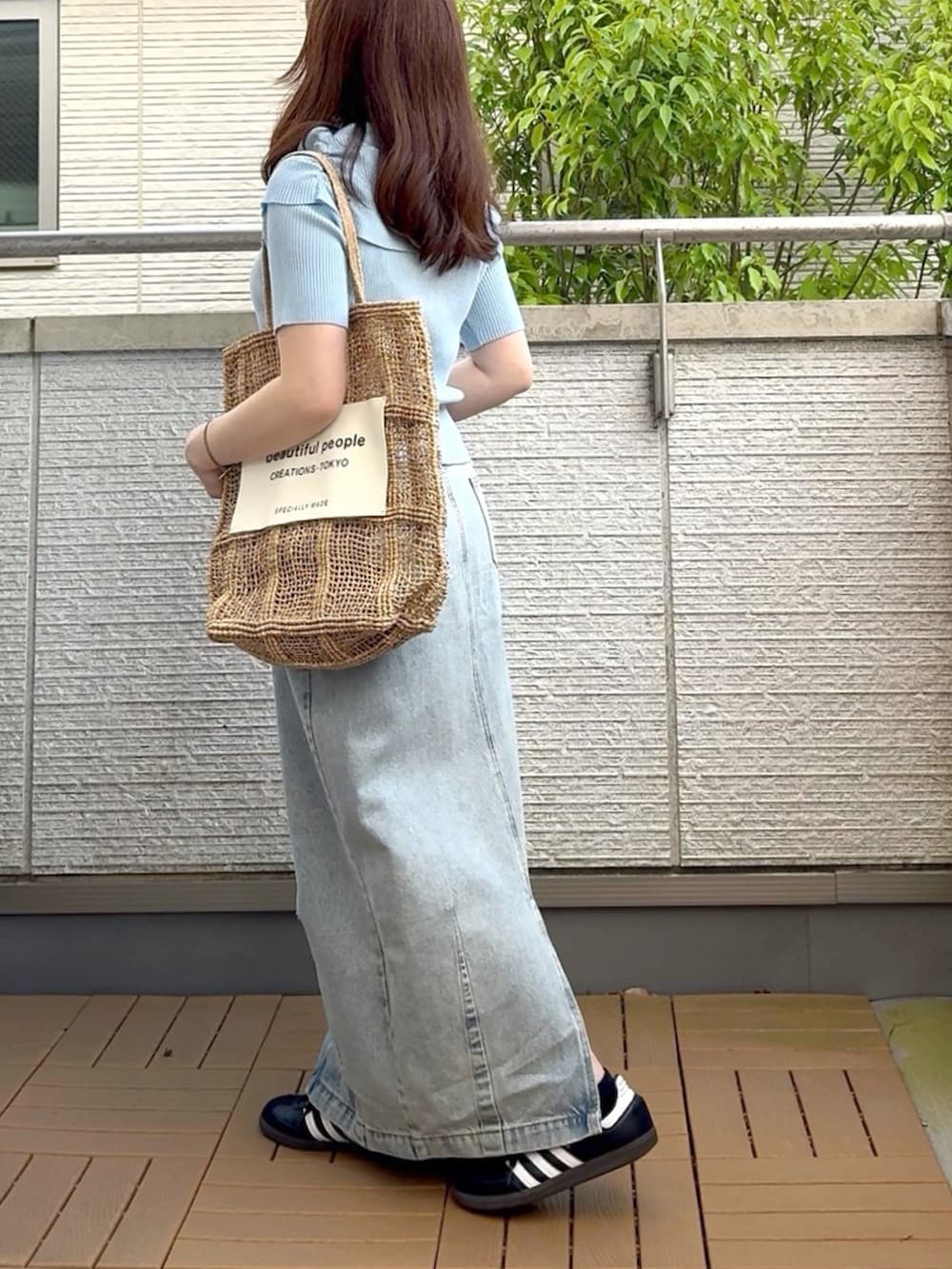 ブルー系のニット/セーター、ブラック系のスニーカー、ブルー系のデニムスカートを着用したレディースの春コーディネートの4枚目の写真