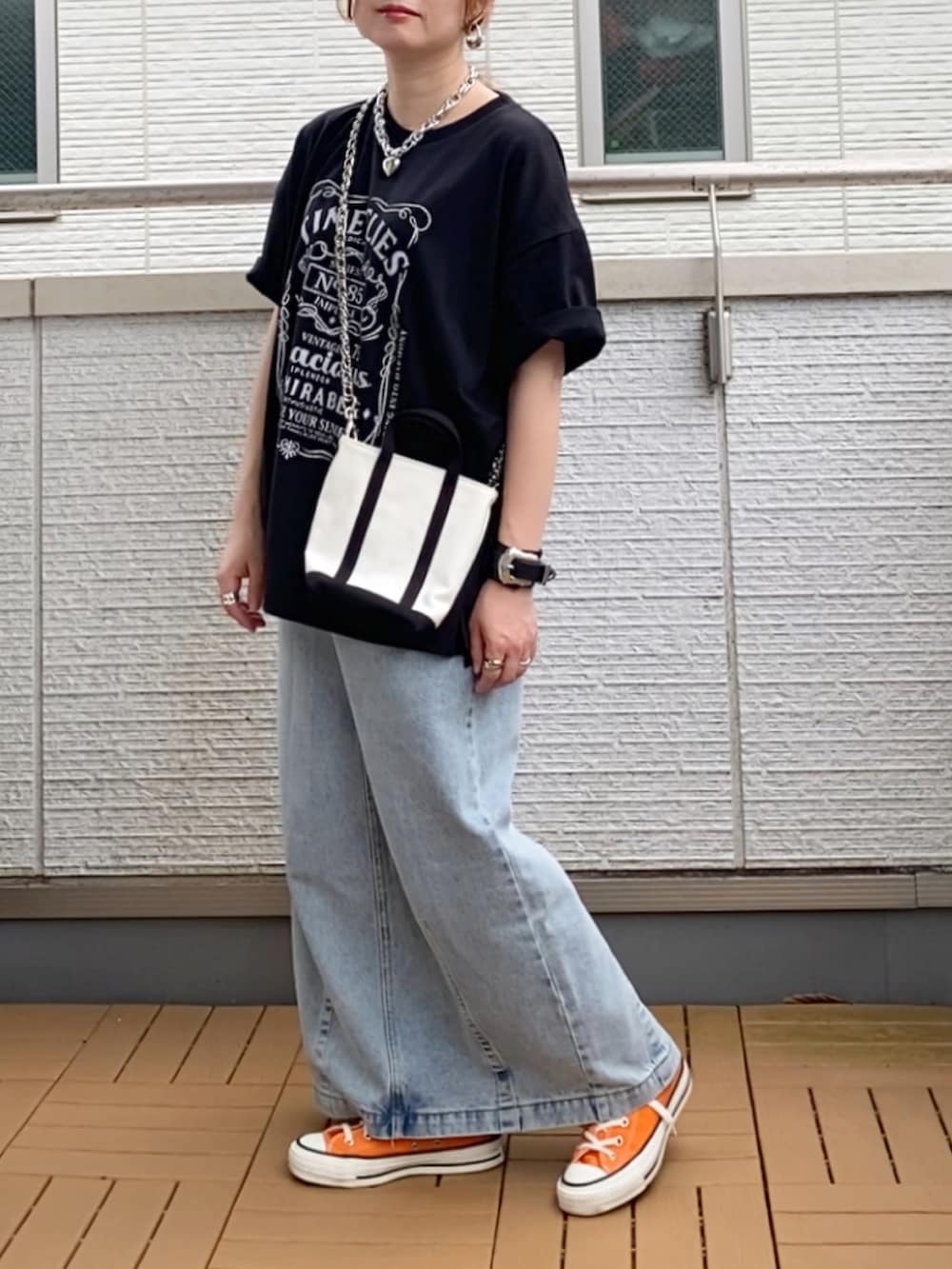 ブラック系のTシャツ/カットソー、ブルー系のデニムスカート、オレンジ系のスニーカーを着用したレディースの夏コーディネートの2枚目の写真