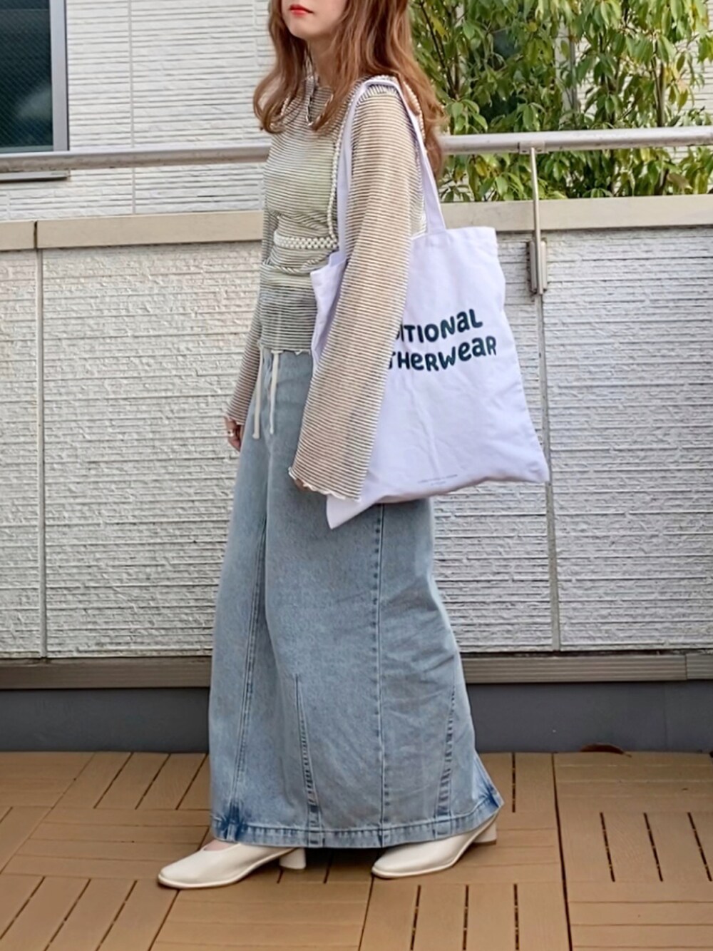 ホワイト系のTシャツ/カットソー、ブルー系のデニムスカート、ホワイト系のトートバッグを着用したレディースの春コーディネートの3枚目の写真