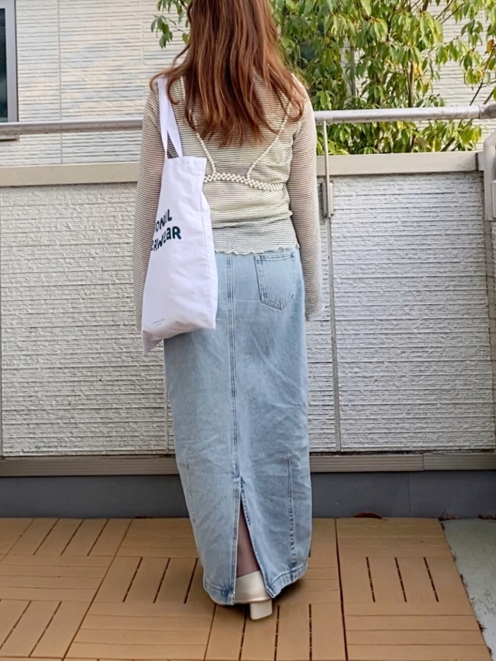 ホワイト系のTシャツ/カットソー、ブルー系のデニムスカート、ホワイト系のトートバッグを着用したレディースの春コーディネートの4枚目の写真