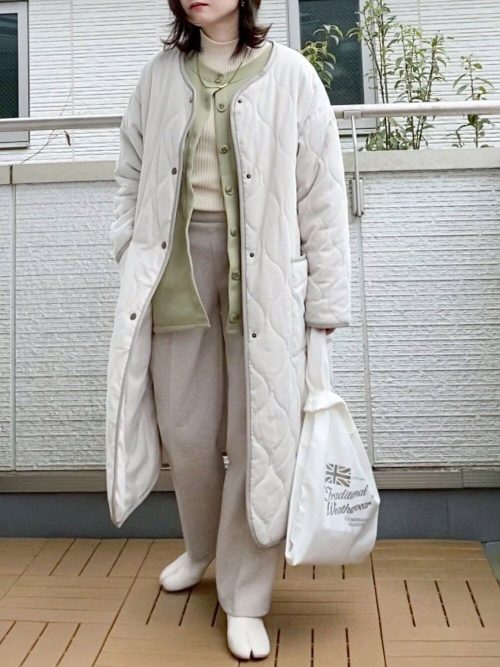 グリーン系のカーディガン/ボレロ、ホワイト系のスラックス、シルバー系のエコバッグ/サブバッグを着用したレディースの冬コーディネートの2枚目の写真
