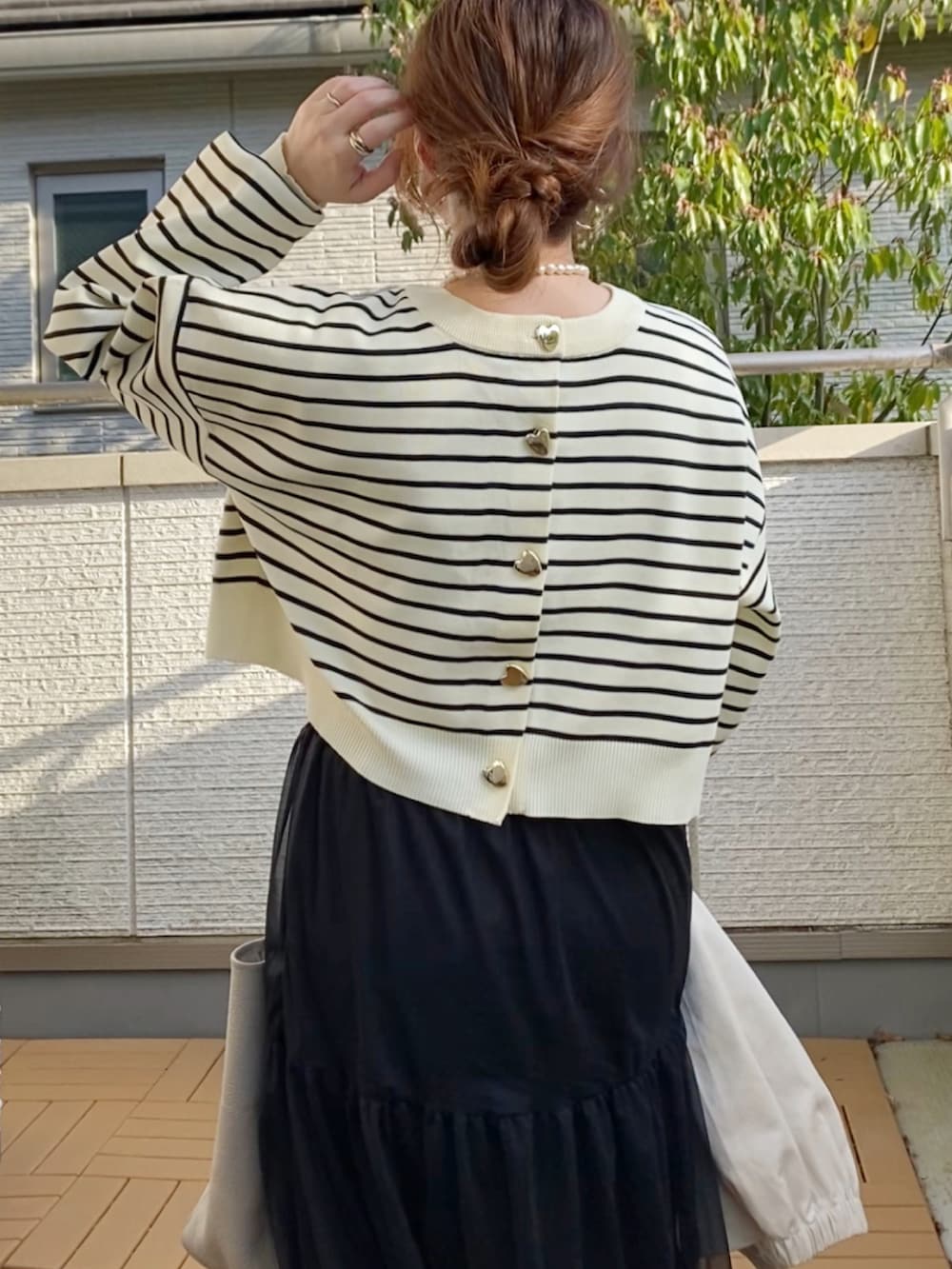 ホワイト系のマウンテンパーカー、ブラック系のカーディガン/ボレロ、ブラック系のスカートを着用したレディースの春コーディネートの5枚目の写真