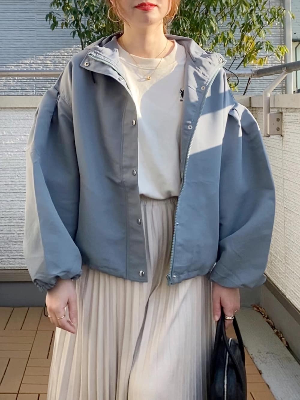 ブルー系のマウンテンパーカー、グリーン系のショルダーバッグ、ホワイト系のスニーカーを着用したレディースの春コーディネートの3枚目の写真