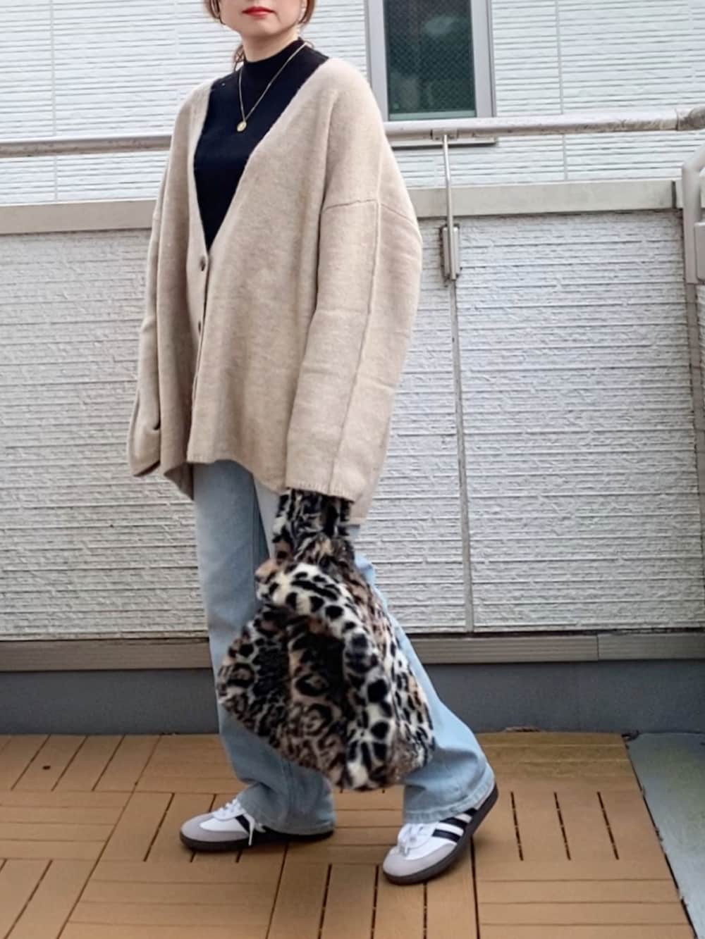 ブラック系のニット/セーター、ベージュ系のカーディガン/ボレロ、ブルー系のデニムパンツを着用したレディースの冬コーディネートの2枚目の写真