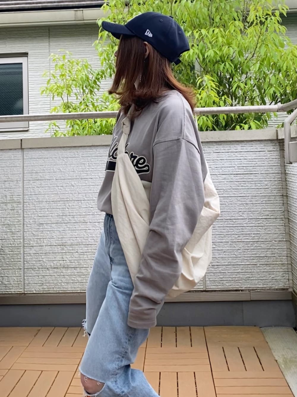 グレー系のTシャツ/カットソー、ブルー系のデニムパンツ、ホワイト系のショルダーバッグを着用したレディースの春コーディネートの4枚目の写真