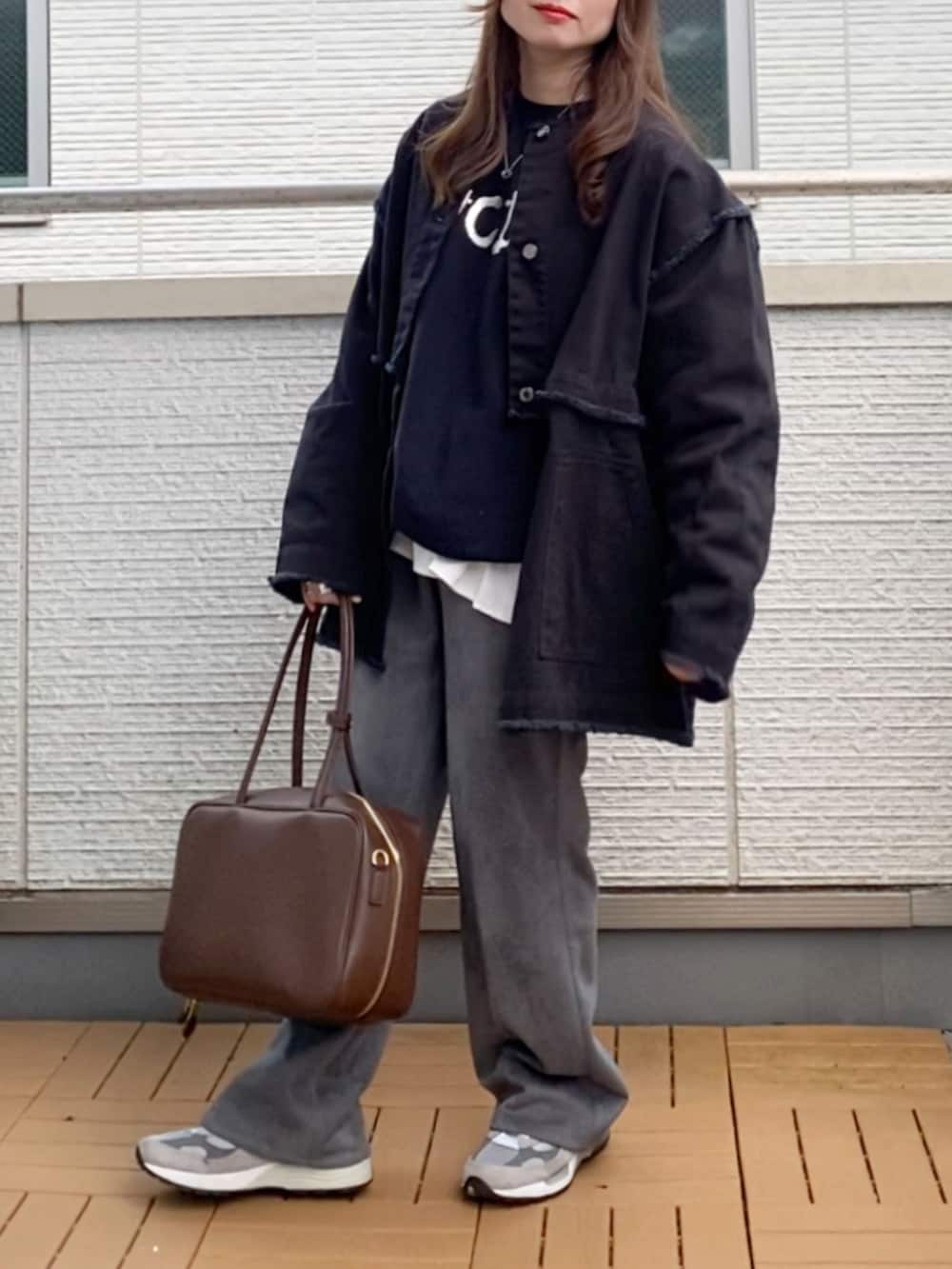 ブラック系のデニムジャケット、ブラック系のスウェット、グレー系のスラックスを着用したレディースの冬コーディネートの2枚目の写真