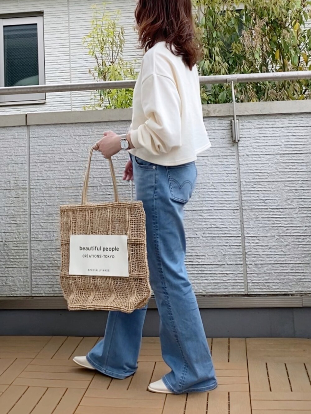 ホワイト系のカーディガン/ボレロ、ブルー系のデニムパンツ、ベージュ系のバッグを着用したレディースの春コーディネートの2枚目の写真