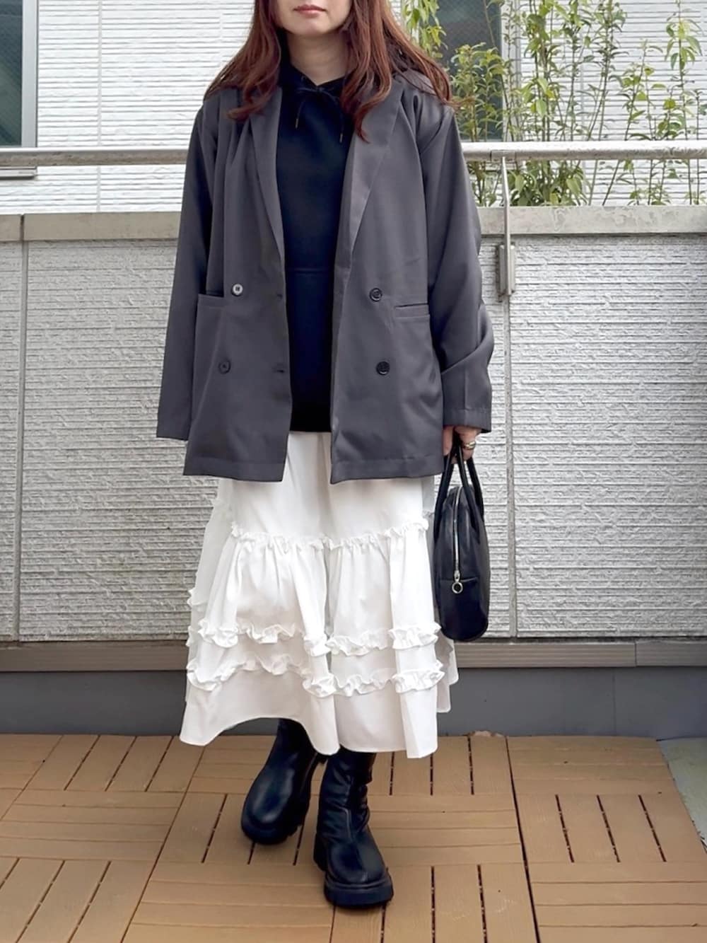 グレー系のテーラードジャケット、ホワイト系のスカート、ブラック系のブーツを着用したレディースの春コーディネートの2枚目の写真