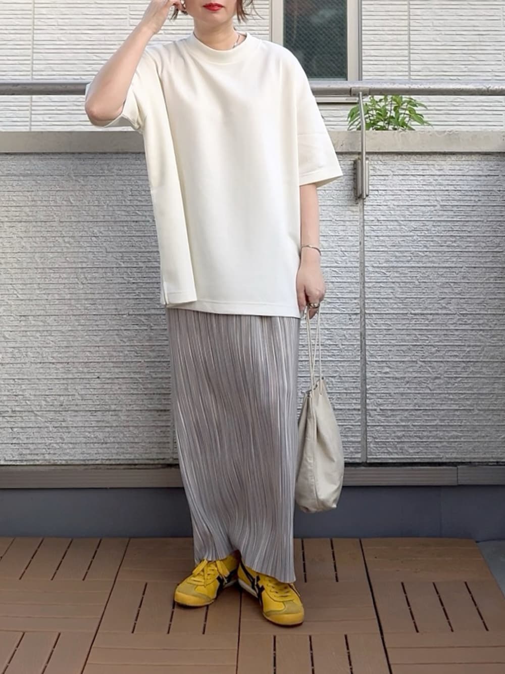 グレー系のスカート、ホワイト系のTシャツ/カットソー、イエロー系のスニーカーを着用したレディースの夏コーディネートの2枚目の写真