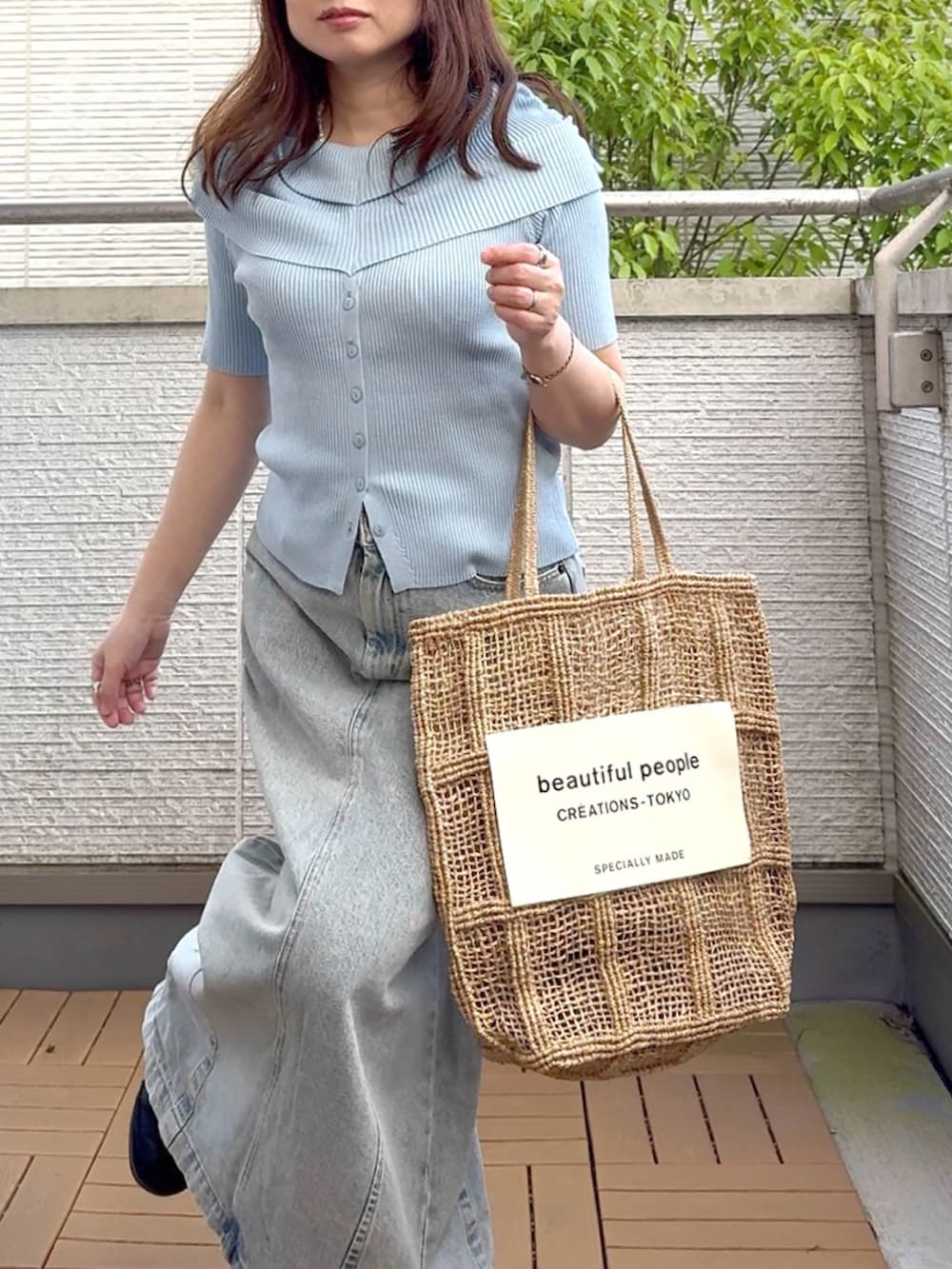 ブルー系のニット/セーター、ブラック系のスニーカー、ブルー系のデニムスカートを着用したレディースの春コーディネートの5枚目の写真