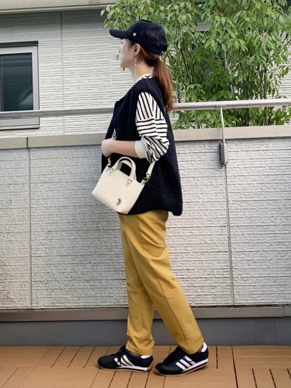 ホワイト系のショルダーバッグ、ブラック系のベスト、ブラック系のTシャツ/カットソーを着用したレディースの秋コーディネートの2枚目の写真