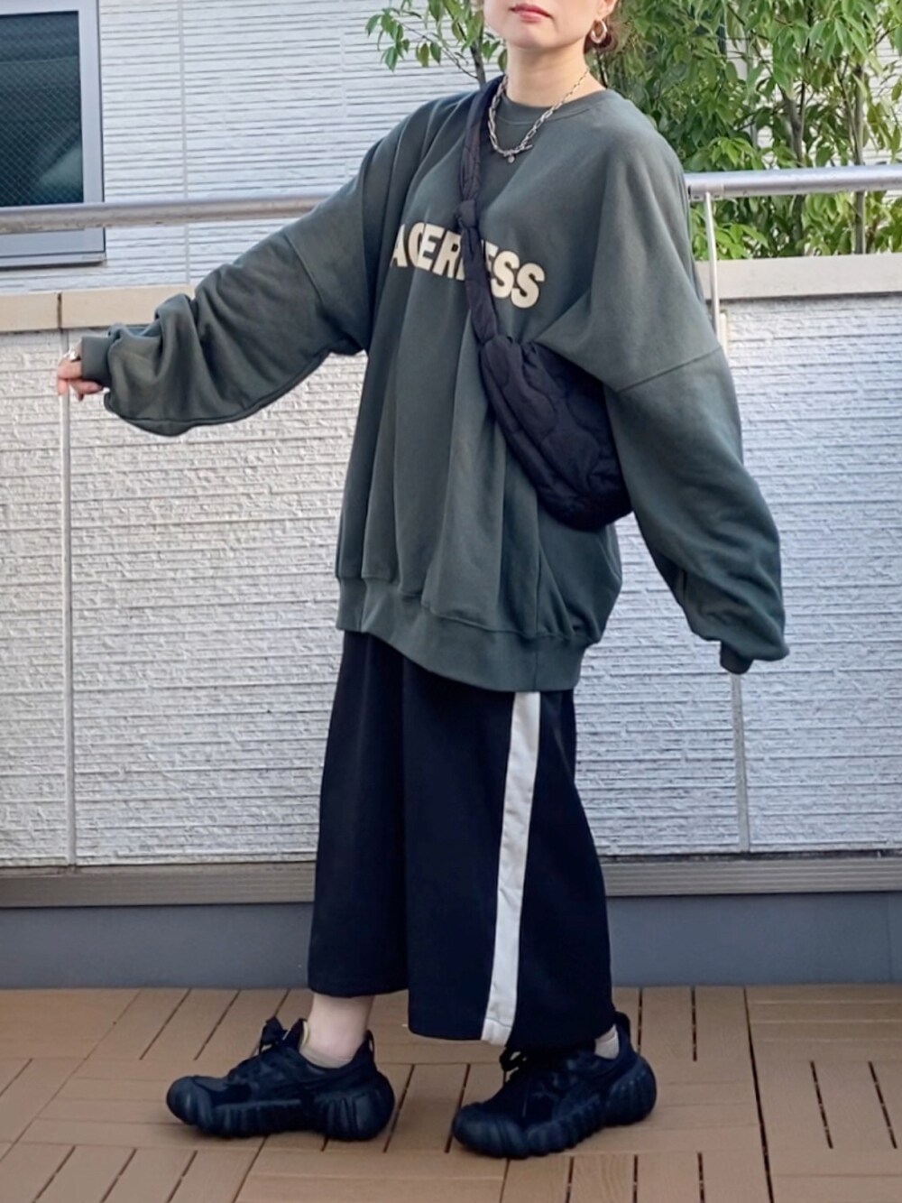 グリーン系のスウェット、ブラック系のスカート、ブラック系のショルダーバッグを着用したレディースの秋コーディネートの3枚目の写真