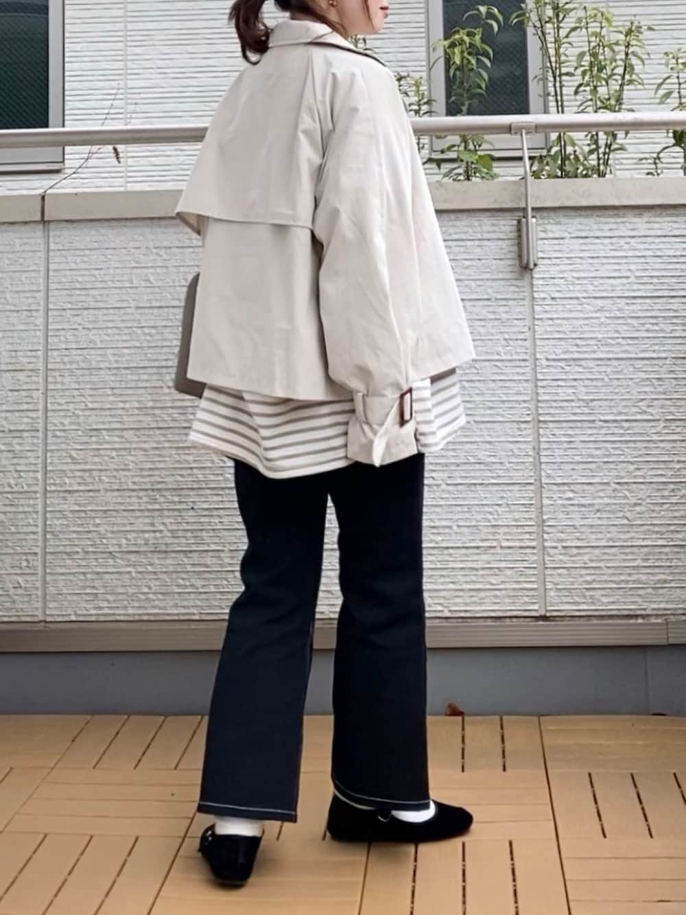 ホワイト系のトレンチコート、ベージュ系のTシャツ/カットソー、ブラック系のデニムパンツを着用したレディースの春コーディネートの3枚目の写真