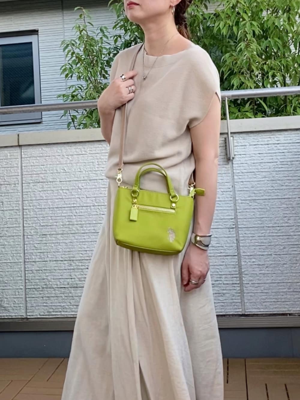 ベージュ系のニット/セーター、ベージュ系のスカート、グリーン系のショルダーバッグを着用したレディースの夏コーディネートの3枚目の写真