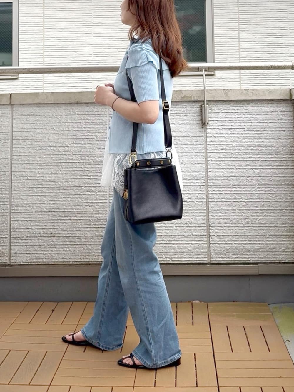 ブルー系のニット/セーター、ホワイト系のキャミソール、ブルー系のデニムパンツを着用したレディースの夏コーディネートの3枚目の写真
