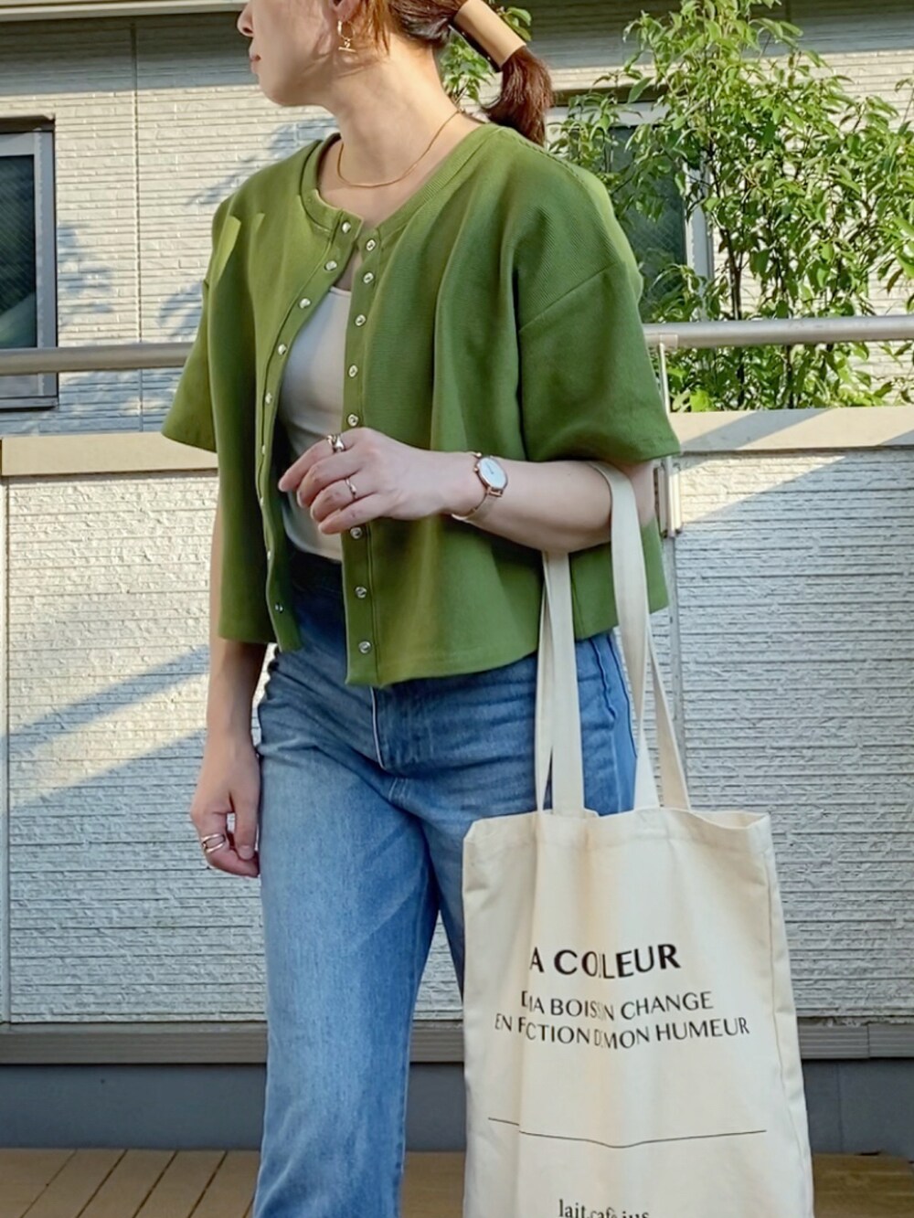 グリーン系のカーディガン/ボレロ、ブルー系のデニムパンツ、ホワイト系のトートバッグを着用したレディースの夏コーディネートの2枚目の写真