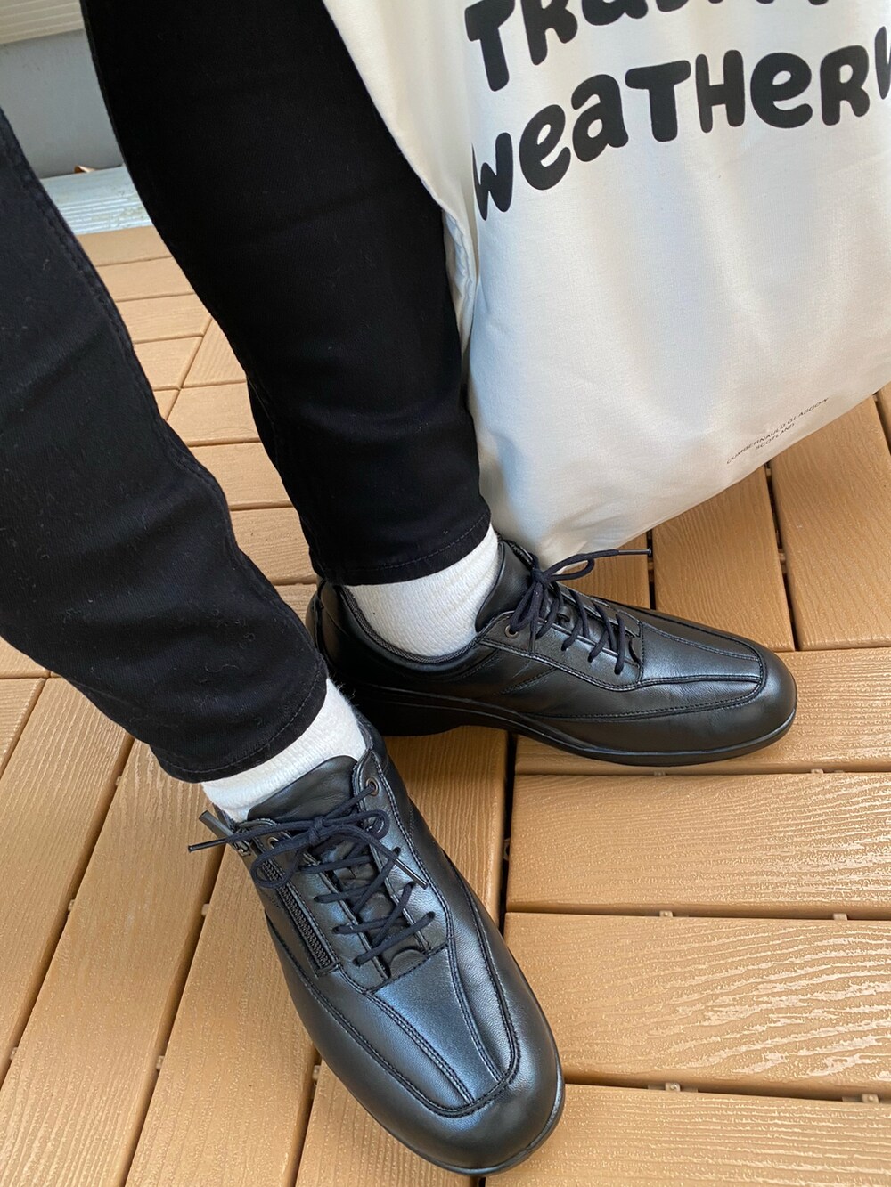 ブラック系のシューズ、ブラック系のその他アウター、ホワイト系のトートバッグを着用したレディースの秋コーディネートの4枚目の写真