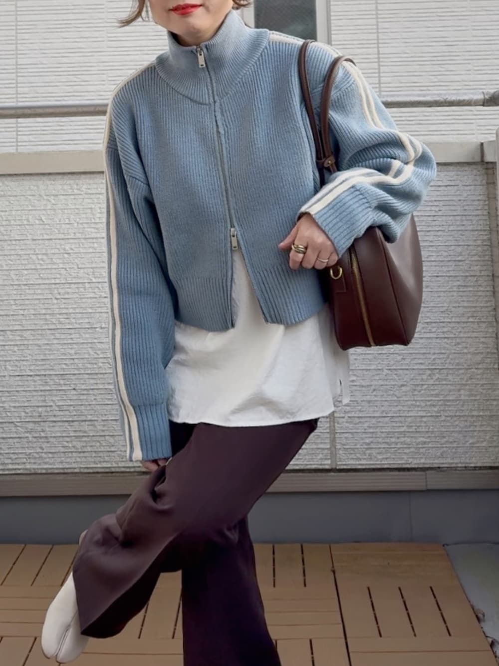 ブルー系のニット/セーター、ホワイト系のシャツ/ブラウス、ブラウン系のスラックスを着用したレディースの冬コーディネートの4枚目の写真