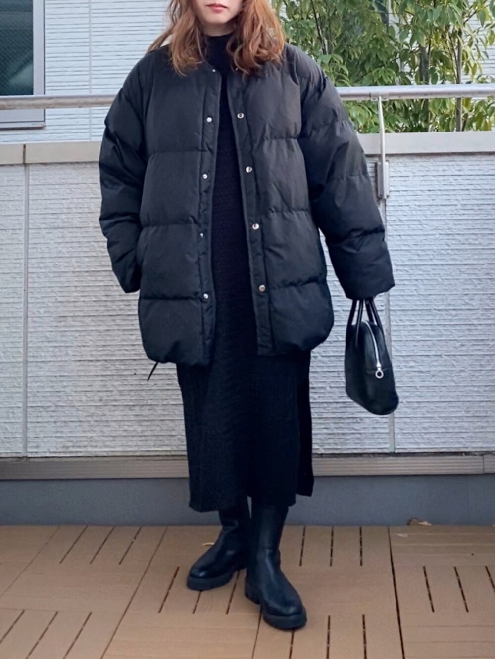 ブラック系のダウンジャケット/コート、ブラック系のワンピース、ブラック系のショルダーバッグを着用したレディースの冬コーディネートの2枚目の写真