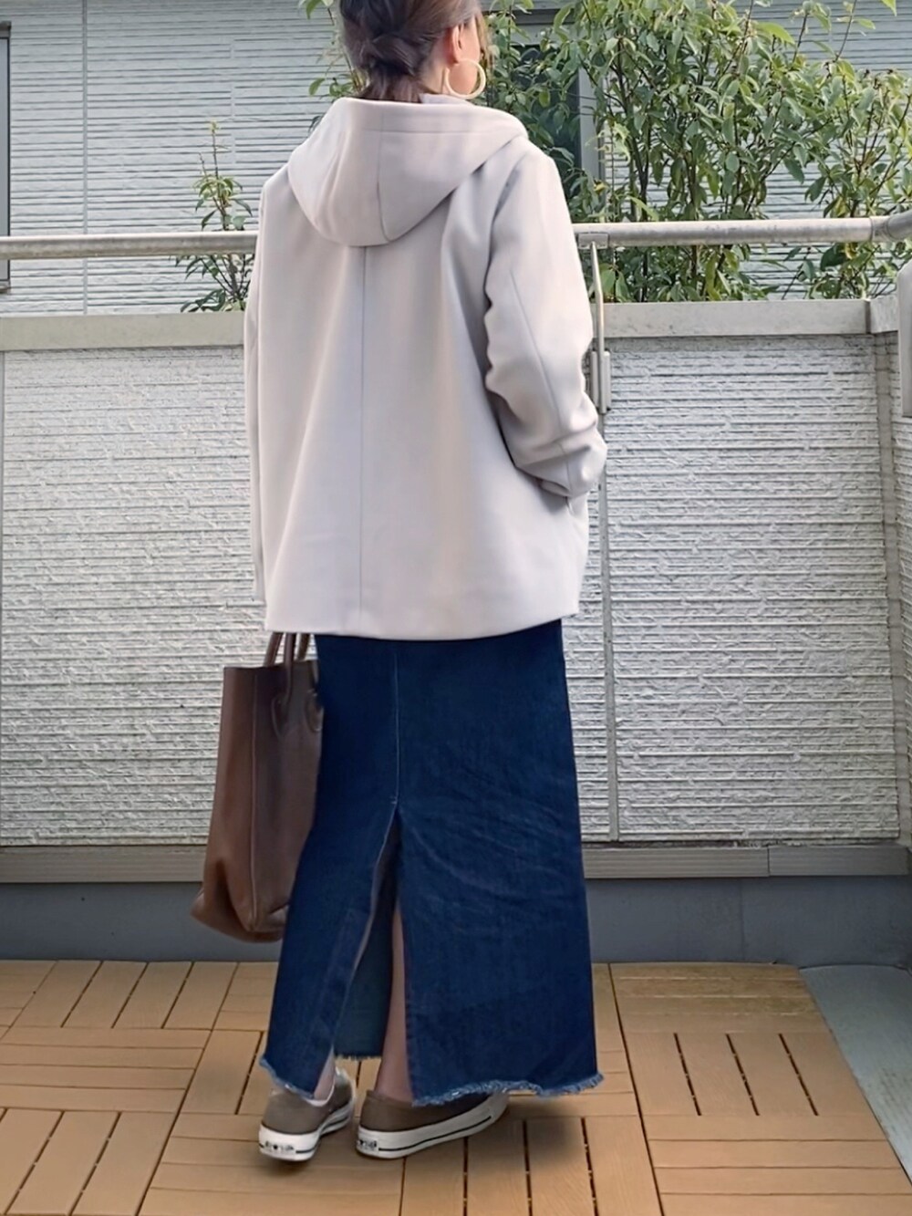 グレー系のノーカラーコート、ベージュ系のTシャツ/カットソー、ブルー系のデニムスカートを着用したレディースの秋コーディネートの3枚目の写真