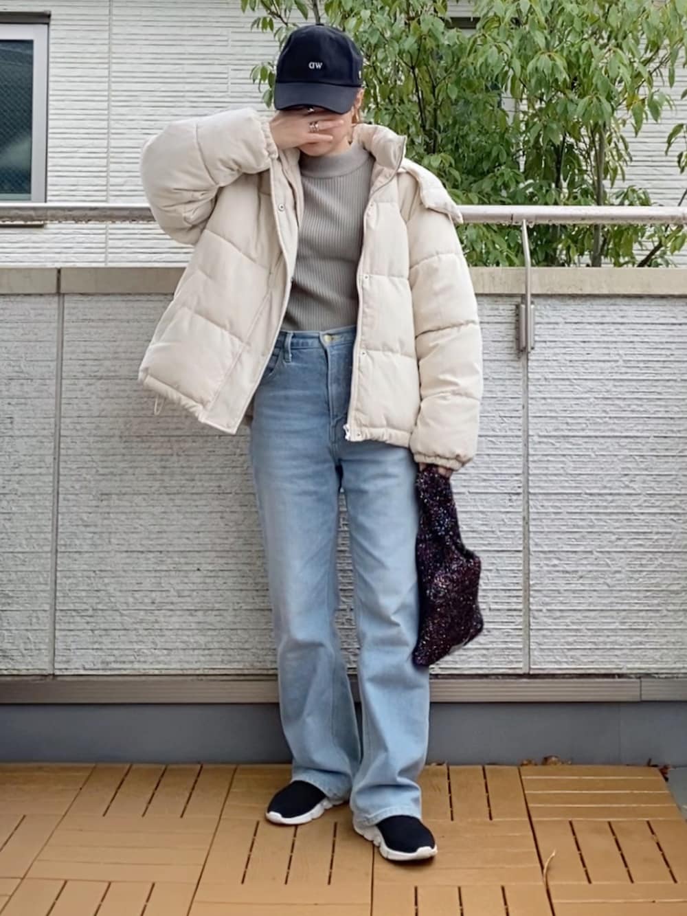 ホワイト系のダウンジャケット/コート、グレー系のニット/セーター、ブルー系のデニムパンツを着用したレディースの冬コーディネートの2枚目の写真