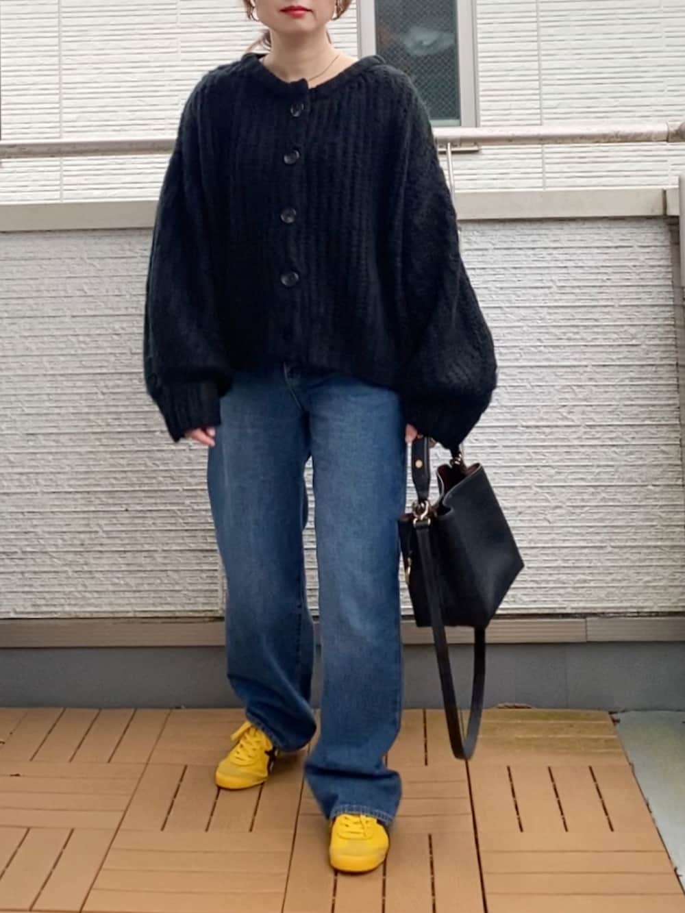 ブラック系のカーディガン/ボレロ、ブルー系のデニムパンツ、ブラック系のショルダーバッグを着用したレディースの秋コーディネートの2枚目の写真