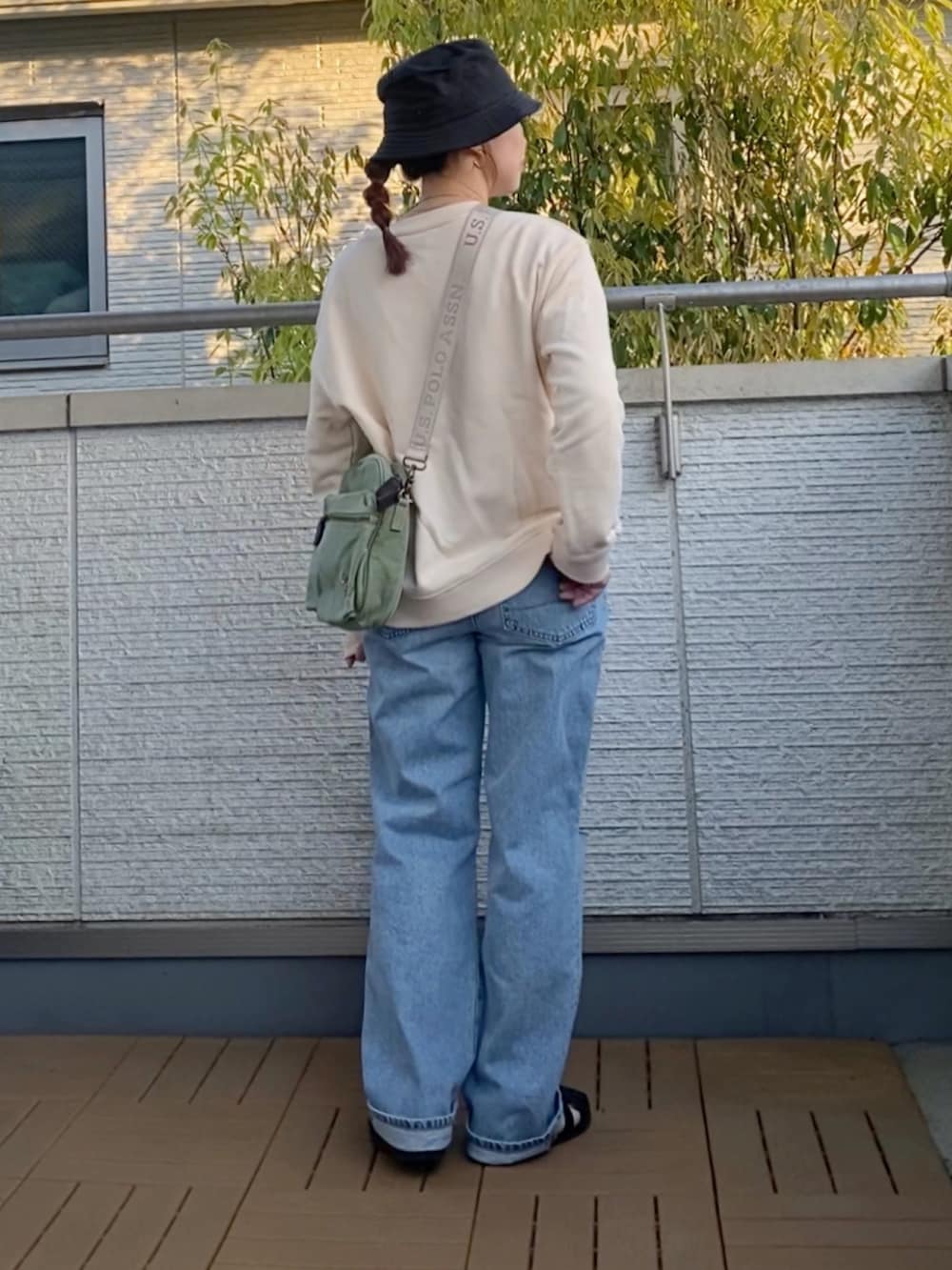 ホワイト系のスウェット、ブルー系のデニムパンツ、グリーン系のショルダーバッグを着用したレディースの春コーディネートの3枚目の写真