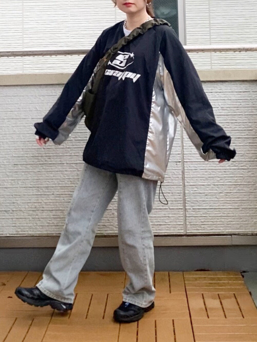 ブラック系のトップス、ブルー系のデニムパンツ、グリーン系のショルダーバッグを着用したレディースの秋コーディネートの2枚目の写真