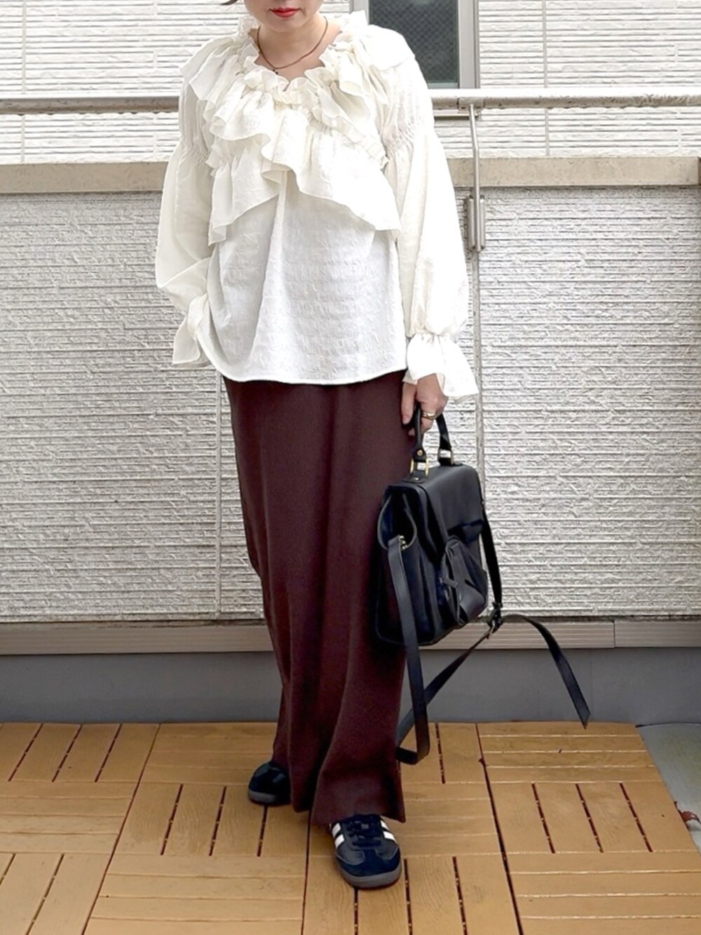 ホワイト系のシャツ/ブラウス、ブラウン系のスカート、ブラック系のハンドバッグを着用したレディースの春コーディネートの2枚目の写真