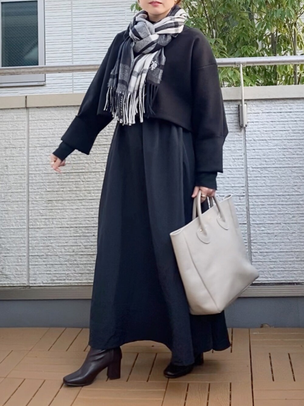 ブラック系のワンピース、ベージュ系のトートバッグ、ブラウン系のブーツを着用したレディースの秋コーディネートの2枚目の写真